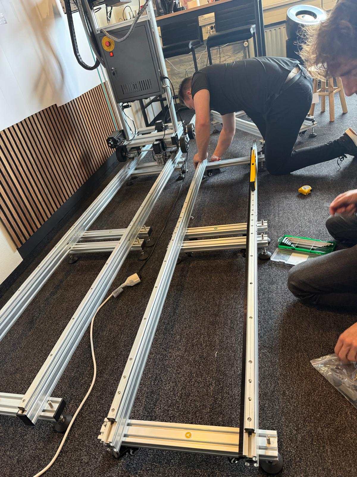 Opbouw van het railsysteem van de wallprinter tijdens training bij Inkture